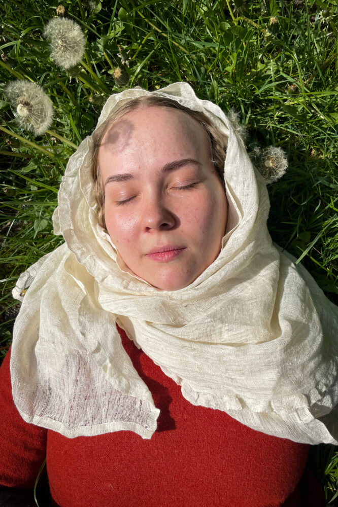 Women poses in medieval headwear kruseler with frilled egge, wrapped around head and neck.