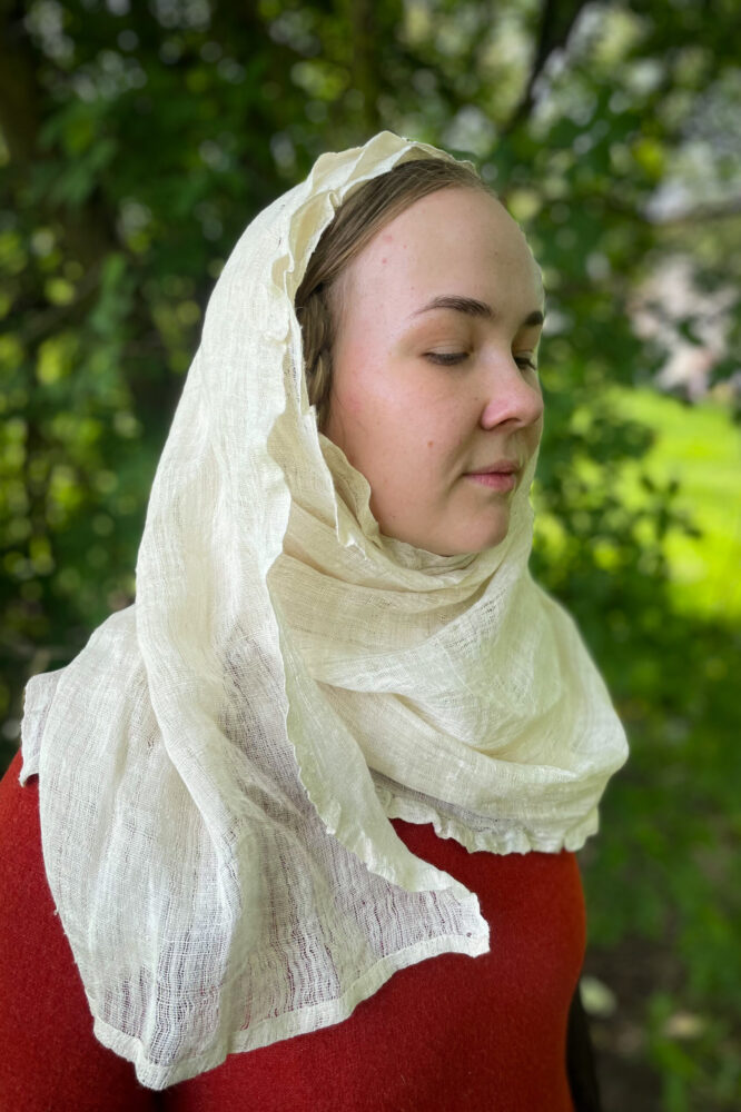 Women poses in medieval headwear kruseler with frilled egge, wrapped around head and neck.