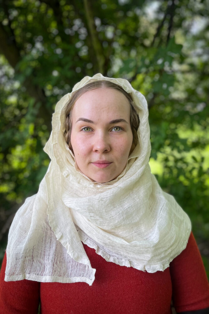 Women poses in medieval headwear kruseler with frilled egge, wrapped around head and neck.